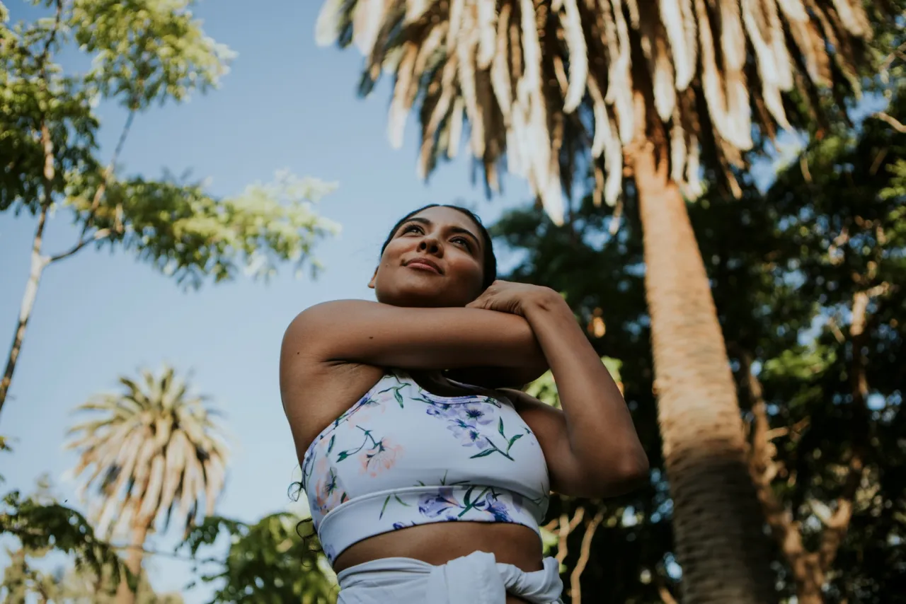 A woman stretching outdoors under palm trees